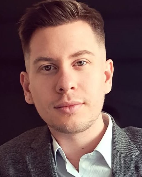 Profilkép egy fiatal férfiről, aki fehér inget és öltönyt hord.